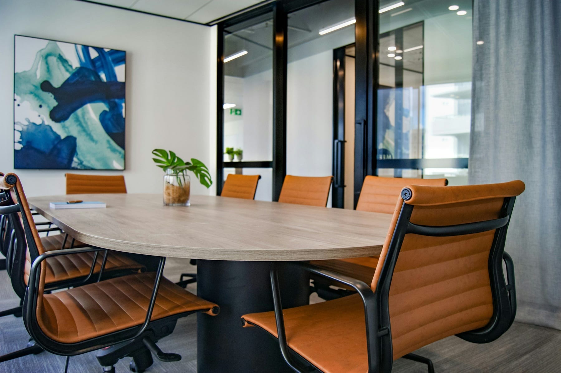 Small conference room with an oval oak table and tan leather chairs