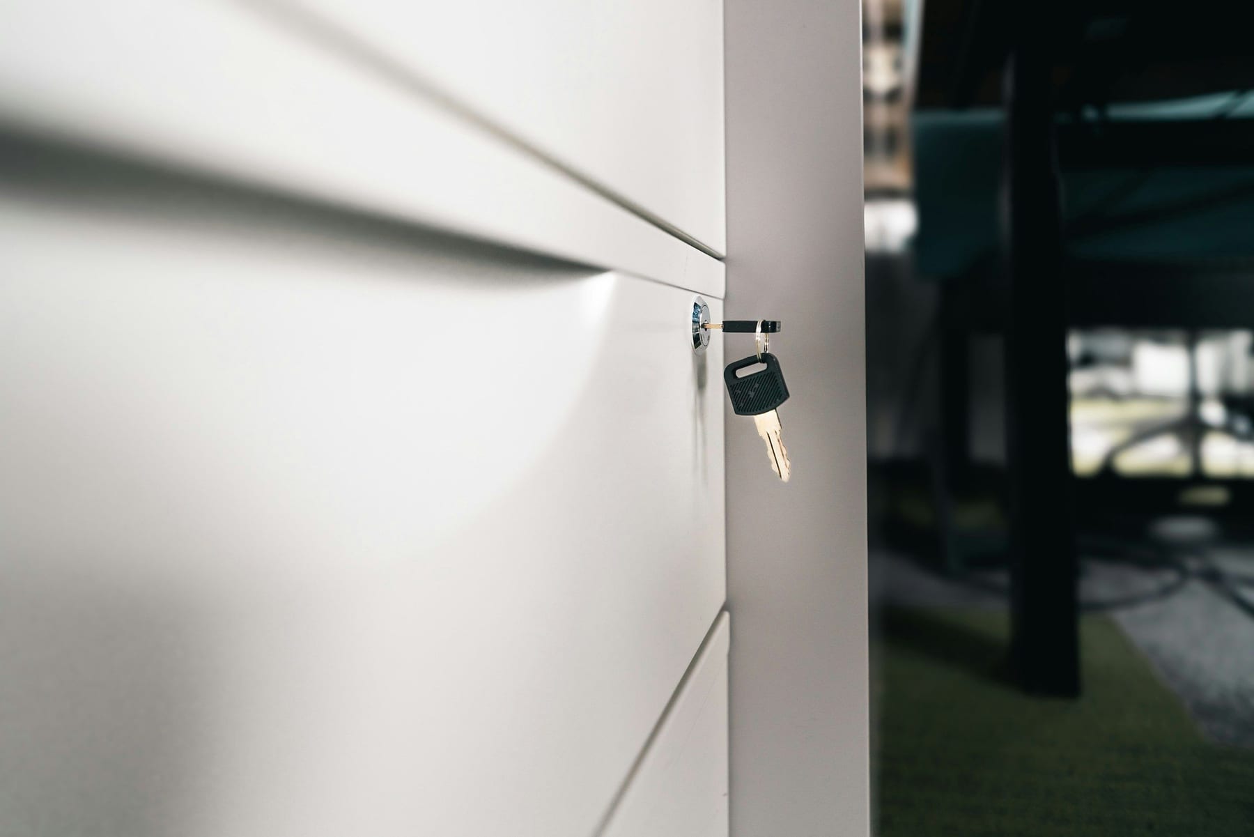 A key sitting in the lock of a white office door