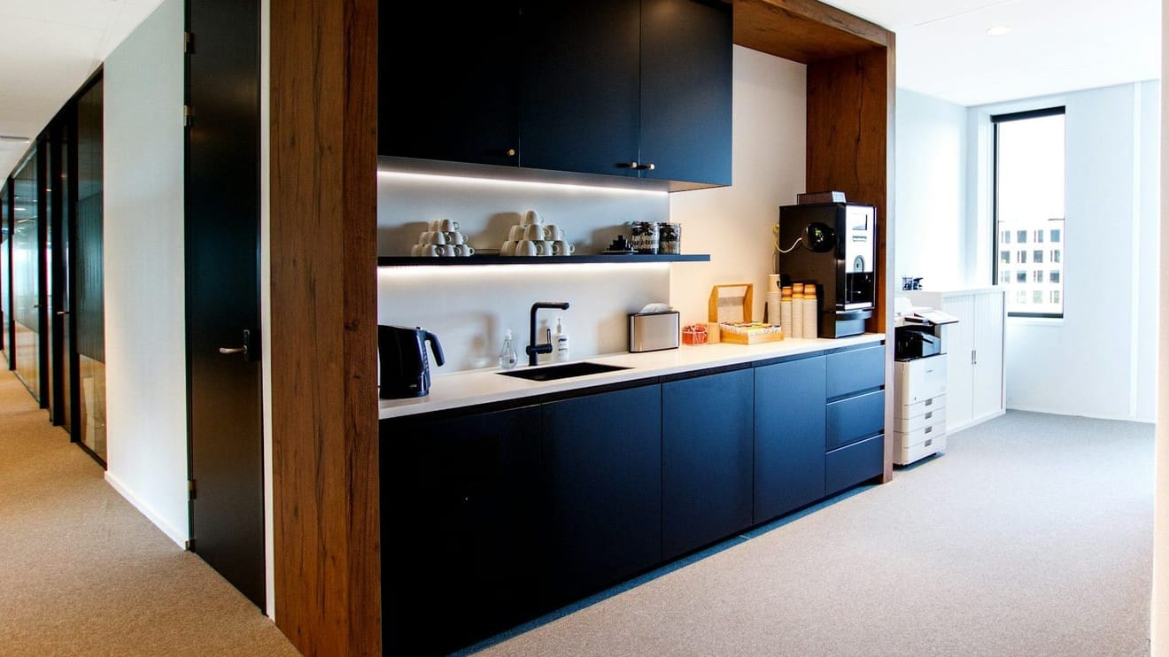 Office kitchenette with navy cabinets, a white counter and a coffee machine